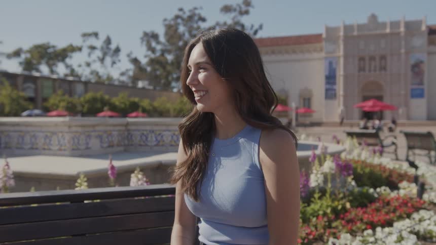 Woman laughs while talking to someone in plaza near flowers