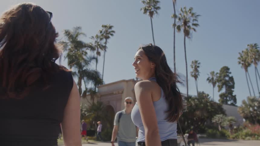 Two women chat while walking on a campus