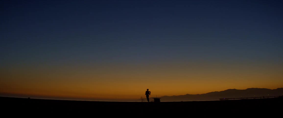 Blue and orange sky on a beach and the silhouette of a person running