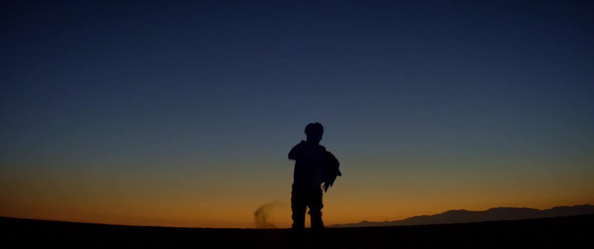 A man in silhouette runs across a desert area