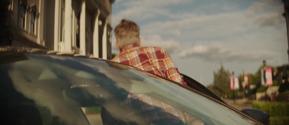 A man and woman exit a car parked on a university campus