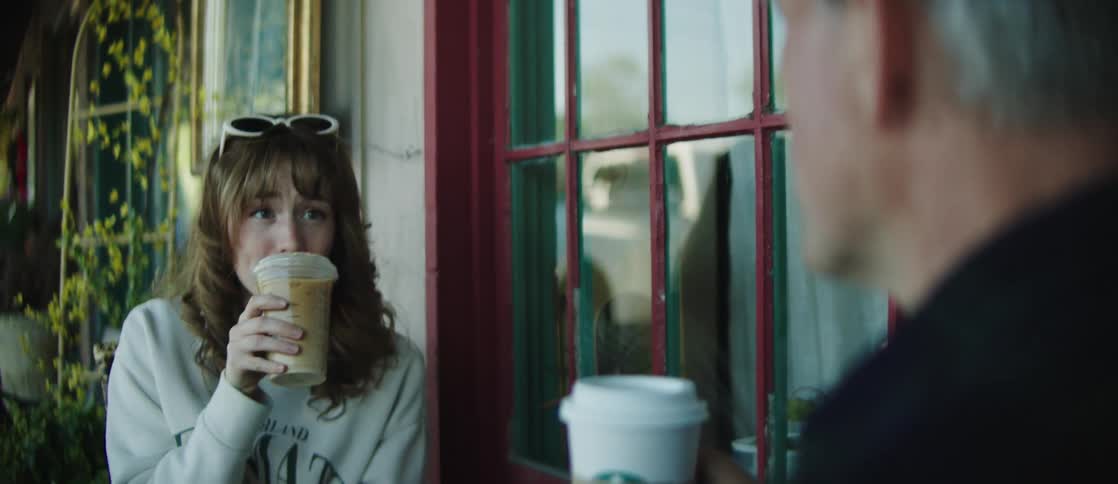 Woman sitting talking to a man while drinking starbucks