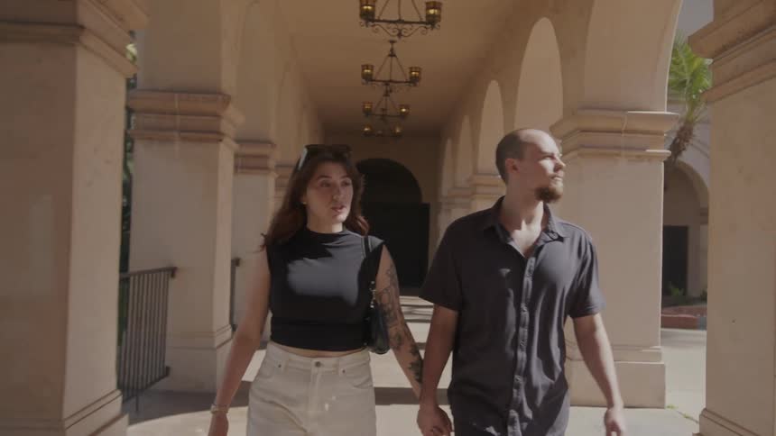 Couple walking together holding hands through an arch in a hallway