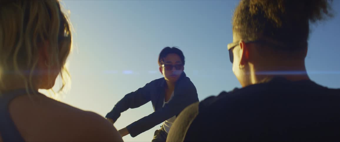 Young man with sunglasses dancing in an openair venue and a couple smiling and enjoying