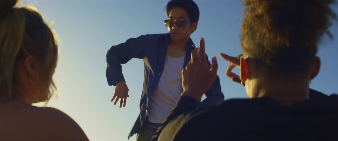 Two young women smile while watching an asian guy dance