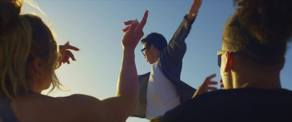 A couple of friends looking at a man dancing under a blue sky