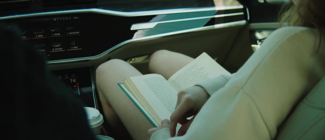 A woman rides in the car with a book on her lap
