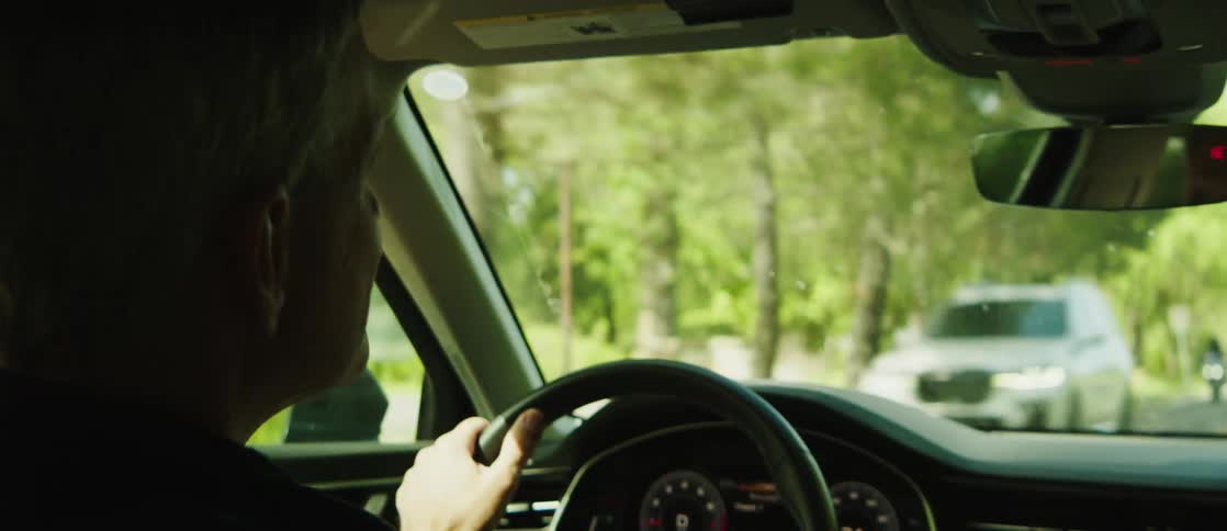 Man driving a car on a road with trees around