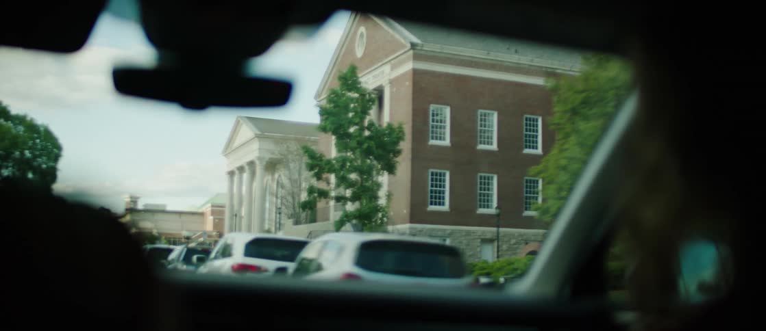 Driver steers car past large buildings in a residential neighborhood