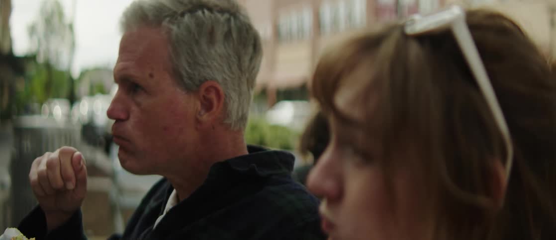 A father and daughter are eating outside
