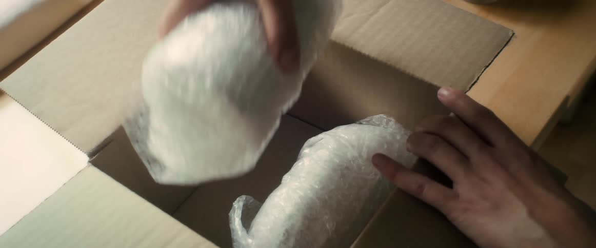 Womans hand holding vases in bubble wrap inside a box