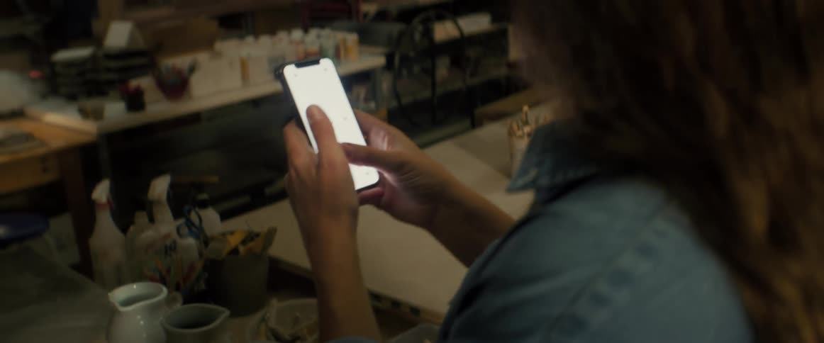 Hands using a smartphone next to a table with handmade vases