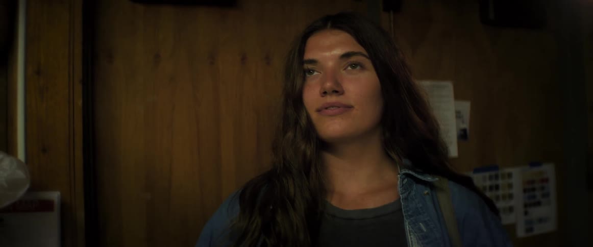 A young woman walks into a room and smiles