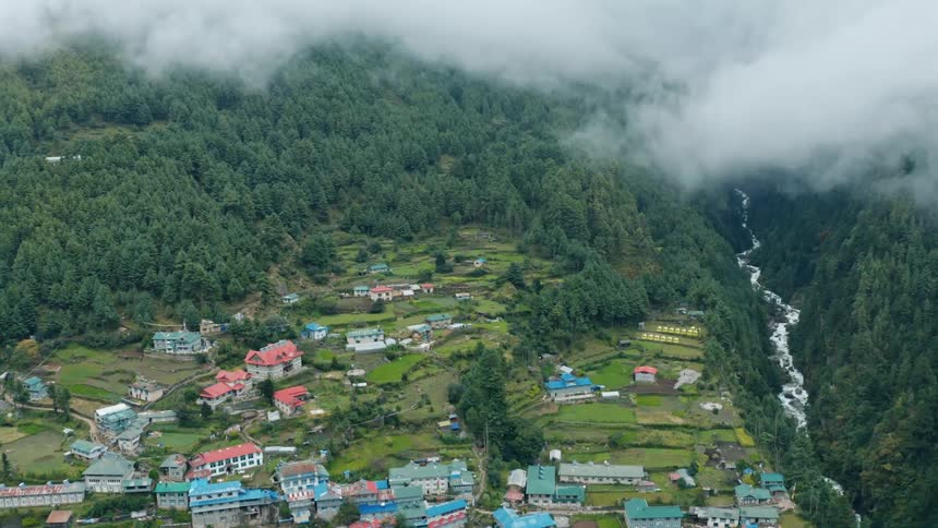 Aerial panorama of a ruined village in the wooded mountains with a river at its side