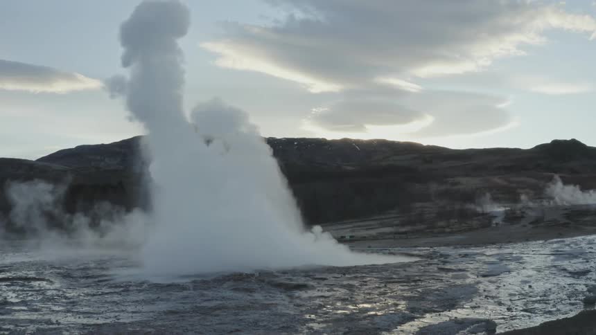 A geyser erupts in a mountain valley