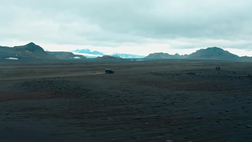 A vehicle drives across a dark plain