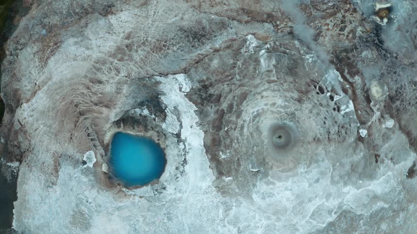 Aerial panorama of rocks with craters emitting steam and turquoise thermal water
