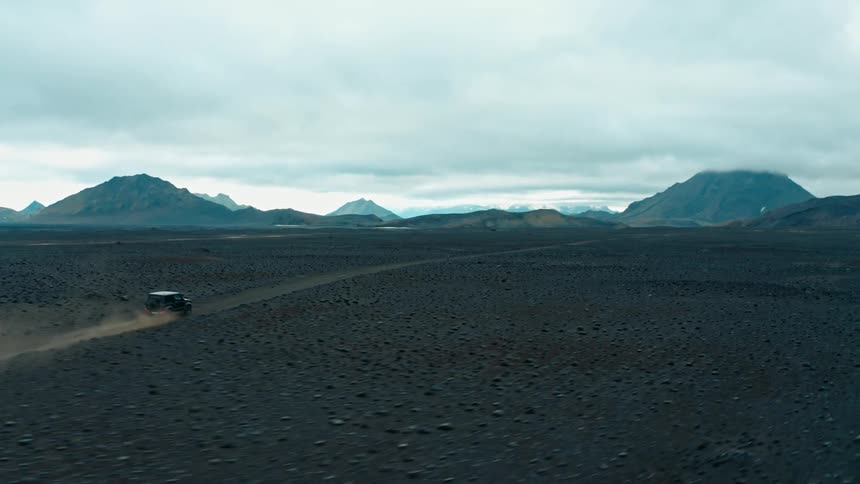 A vehicle drives on a road crossing a vast mountain valley