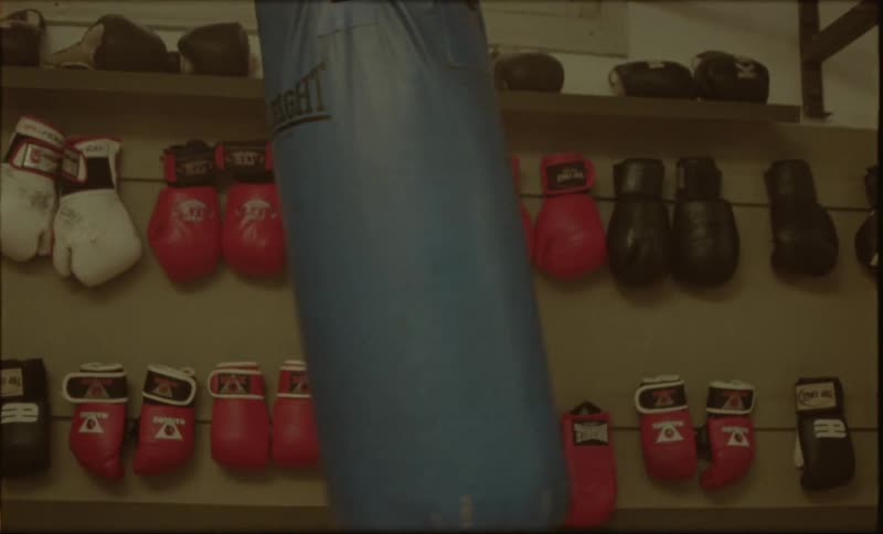 Moving punching bag and a wall with boxing gloves in the background