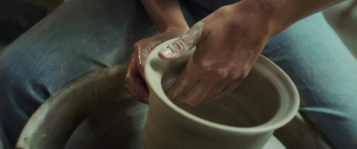 A young woman creates a piece of pottery on a spinning wheel