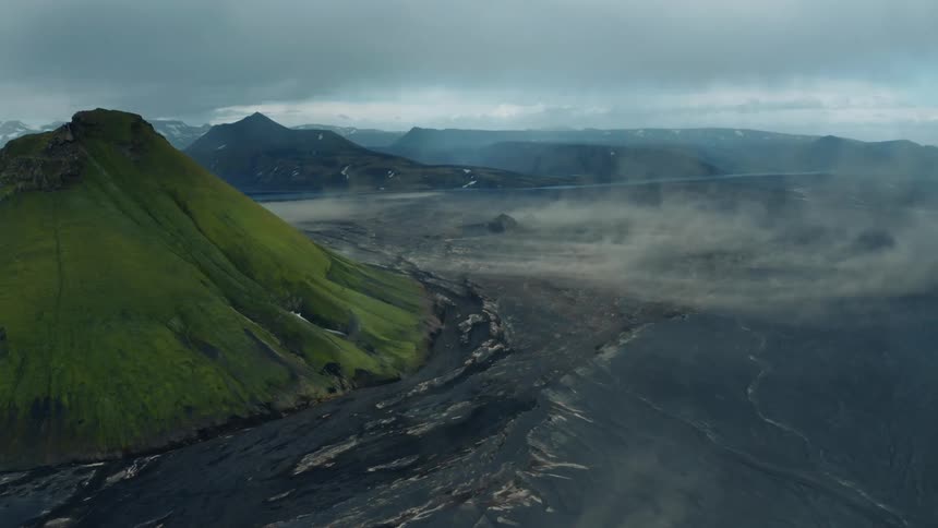 Steam rises from a vast plain near mountains