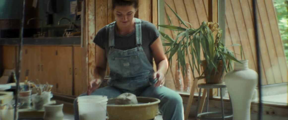 Woman throwing a lump of clay onto a pottery wheel