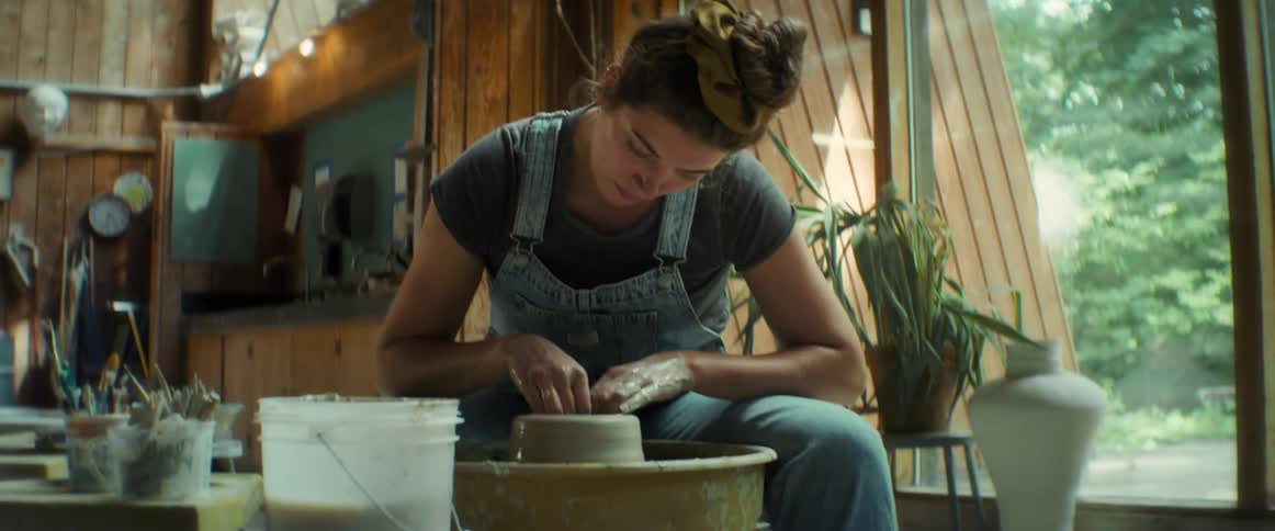 Woman sitting producing a clay vase indoors