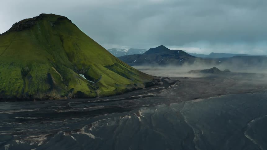Aerial landscape of mountains with mosses and natural wear with black soil around them on a cloudy day