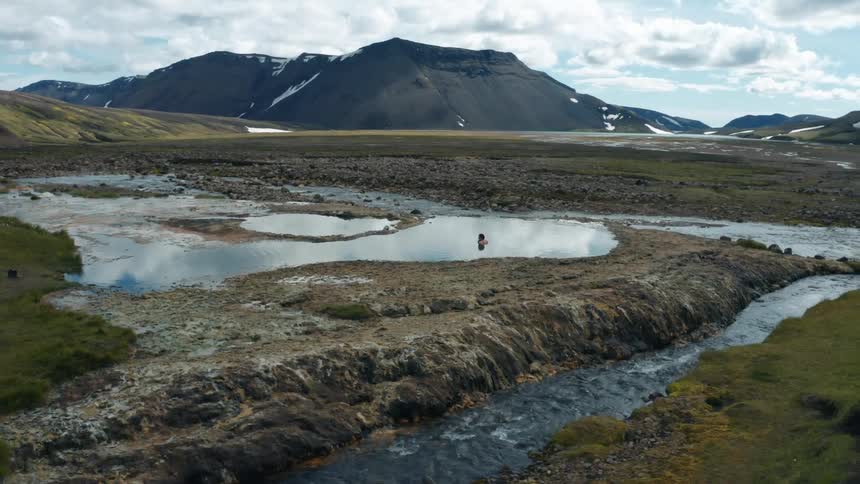 An object floats in a lake near a river in a mountain valley