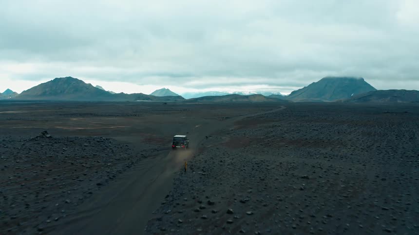 A vehicle drives on a road across a vast plain