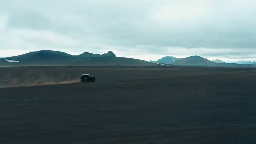 A vehicle drives across a large mountain valley