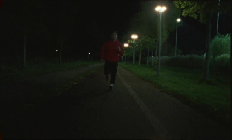 A man jogging on a road at night