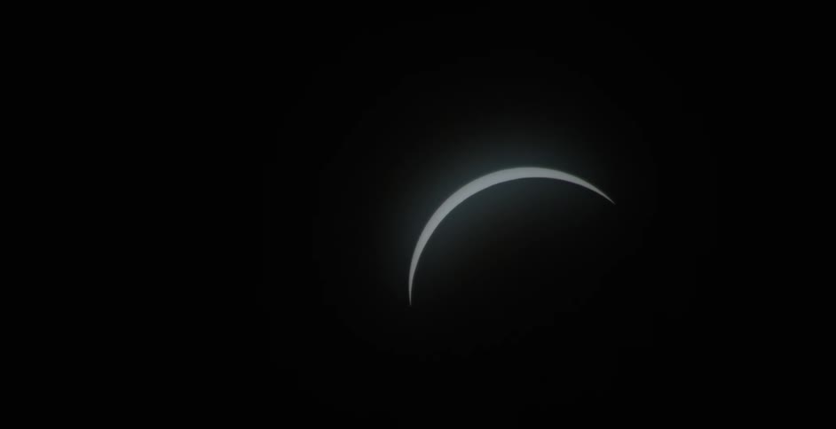 In the darkness of the night sky a sliver of the moon is visible