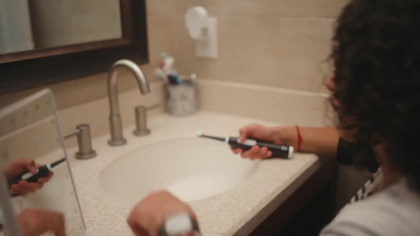Woman in a wheelchair brushes her teeth then rinses the toothbrush