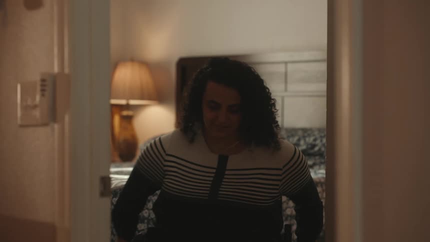 A woman wheels out of the bedroom in a wheelchair