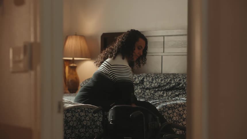 A disabled woman gets out of bed into a wheelchair at home