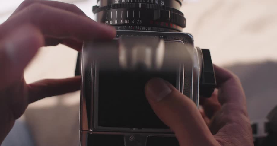 Hands holding a vintage camera with a viewfinder showing a focused image