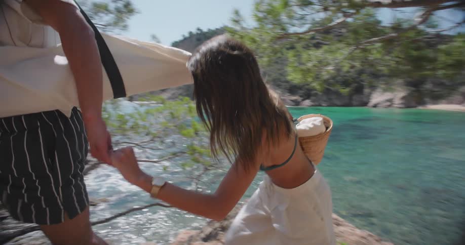 Man helps woman climb promontory overlooking cove