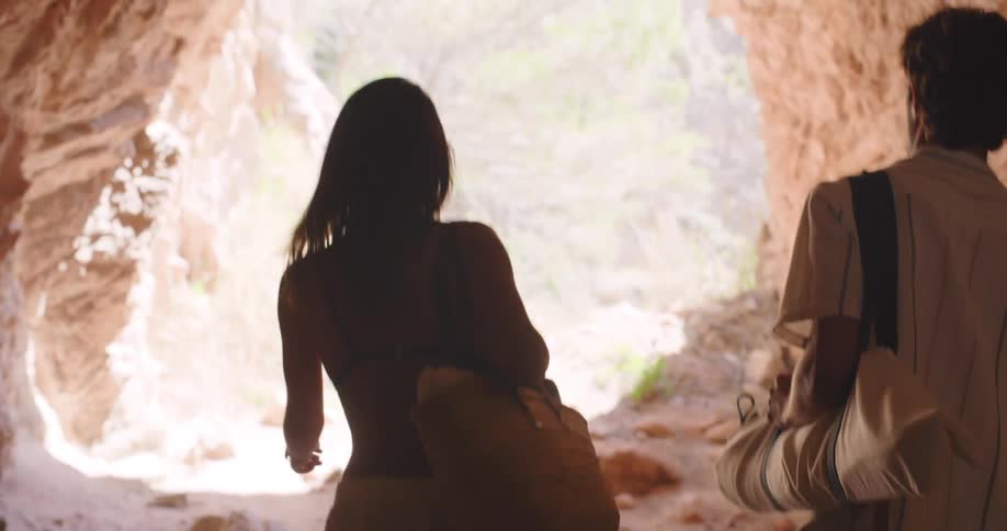 Back view of a couple walking in a cave in a natural environment