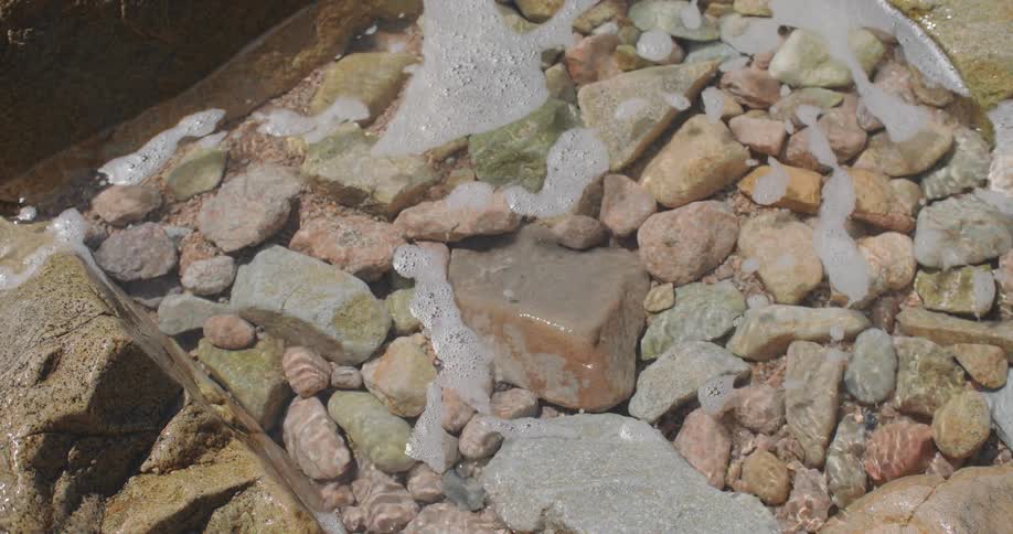 Foamy waves wash over a pile of rocks