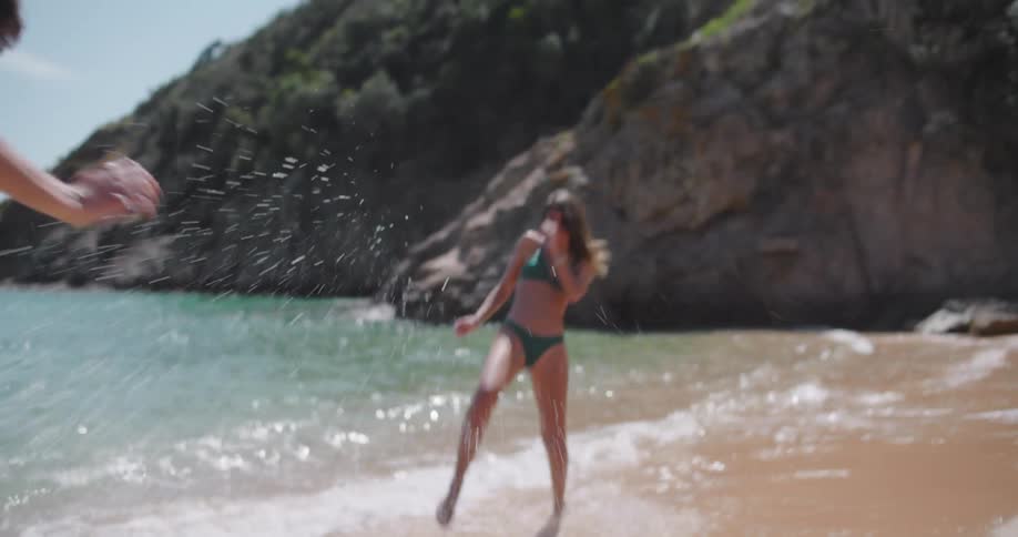 Couple playing on the beach throwing sea water on each other