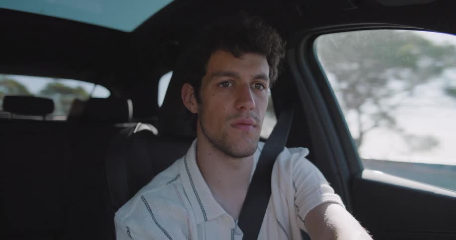 A young man drives a car on a sunny day