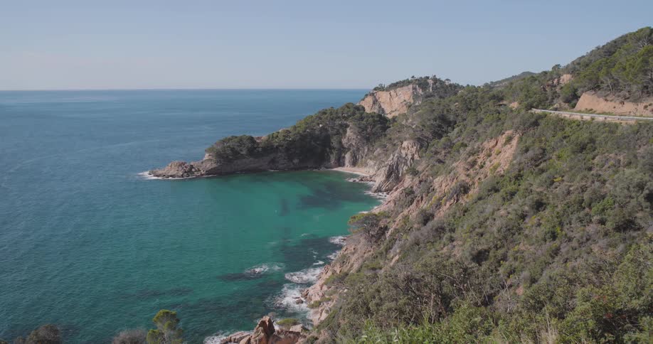 A rugged cliff overlooking the turquoise waters of cala futadera a beach on the coast of spain