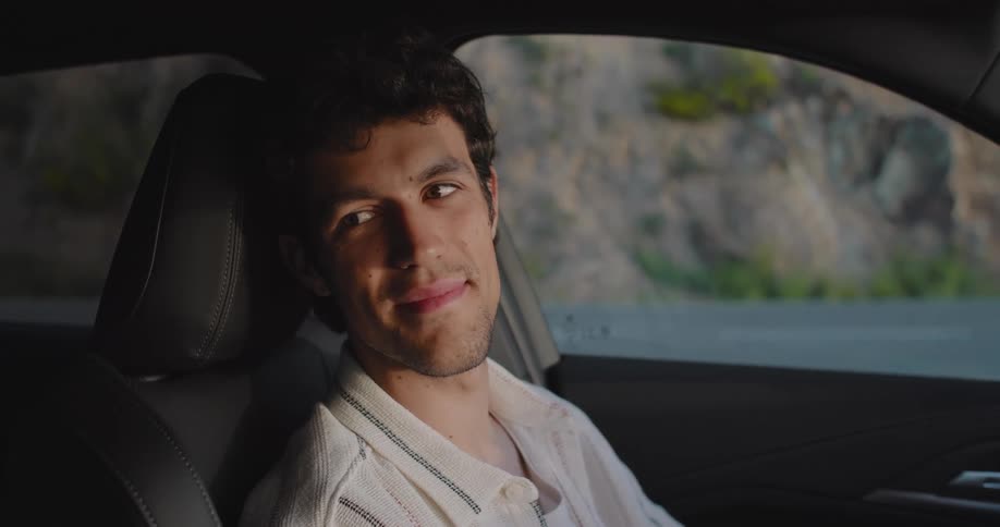 A man smiles in his car