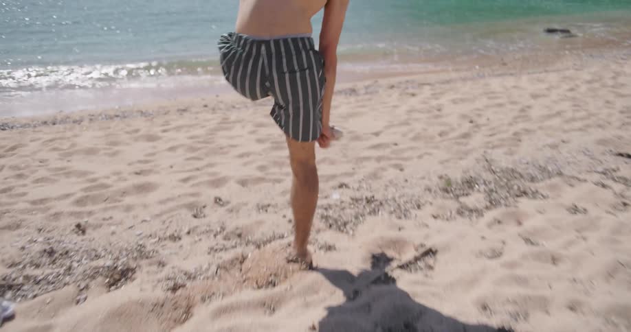 Man taking off his socks and running towards the sea on the beach