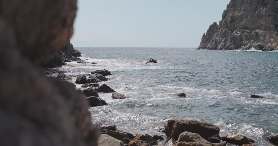 Foamy waves wash across a rocky shoreline