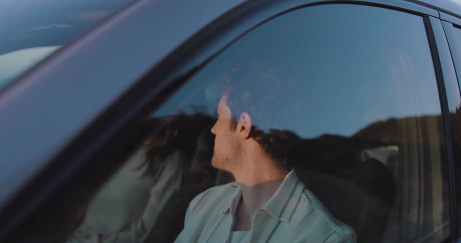 A young couple looking at the sunset from a car