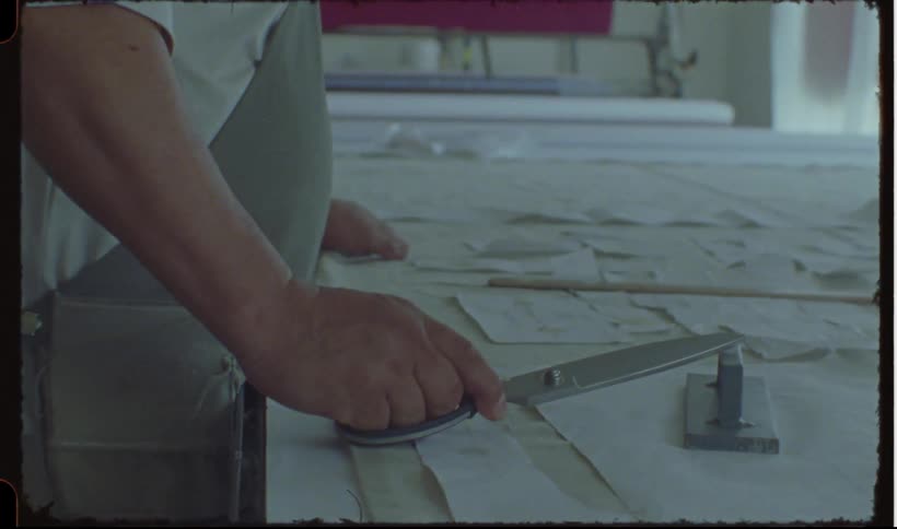 Person holding scissors and sorting papers on a table
