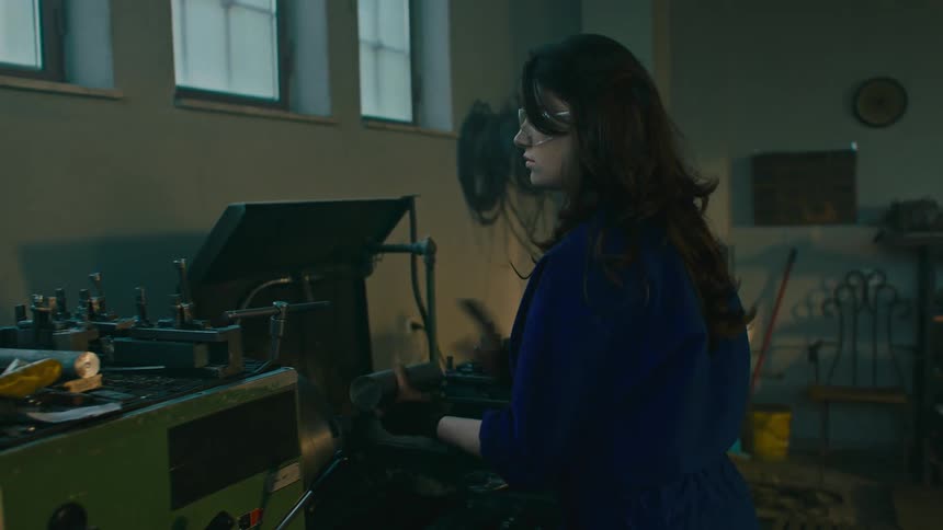 A woman working on a lathe or milling machine in a workshop