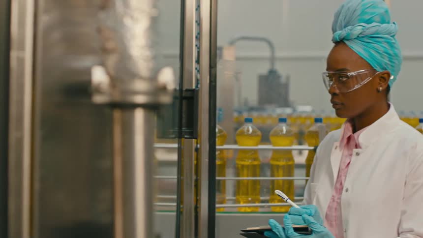 A worker supervises a production line for vegetable oil